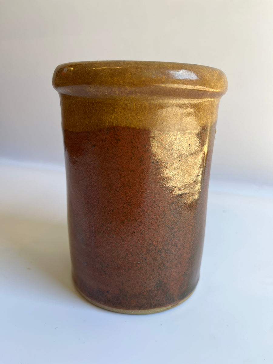 Up close of Cylindrical brown glazed vase with defined rim to show light brown top glaze and darker red brown bottom glaze 